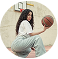 A person with long hair, wearing a white shirt and gray pants, crouches on a basketball court holding a basketball, with a hoop in the background—symbolizing hope and resilience on the journey to opioid addiction treatment.